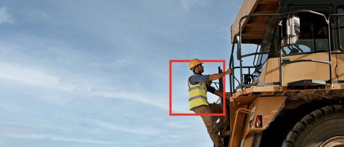 Worker climbing machinery on site